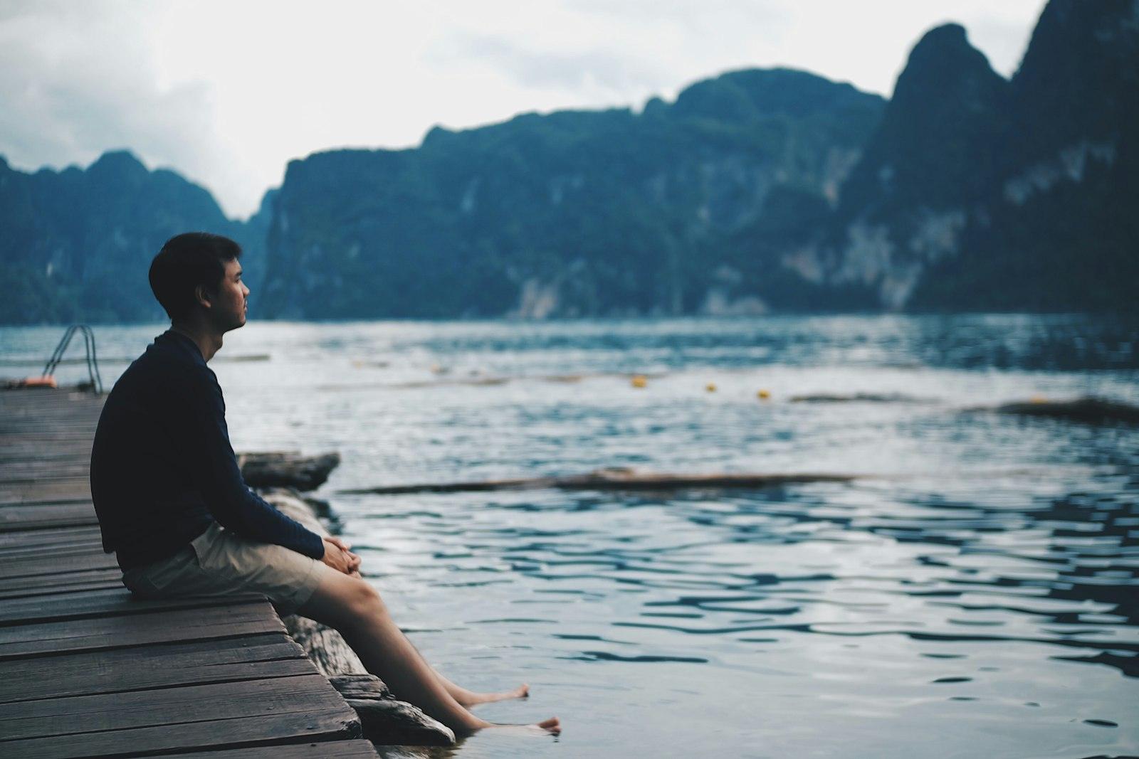 Ein Mann sitzt ruhig am Wasser und richtet seinen Blick bewusst nach vorn