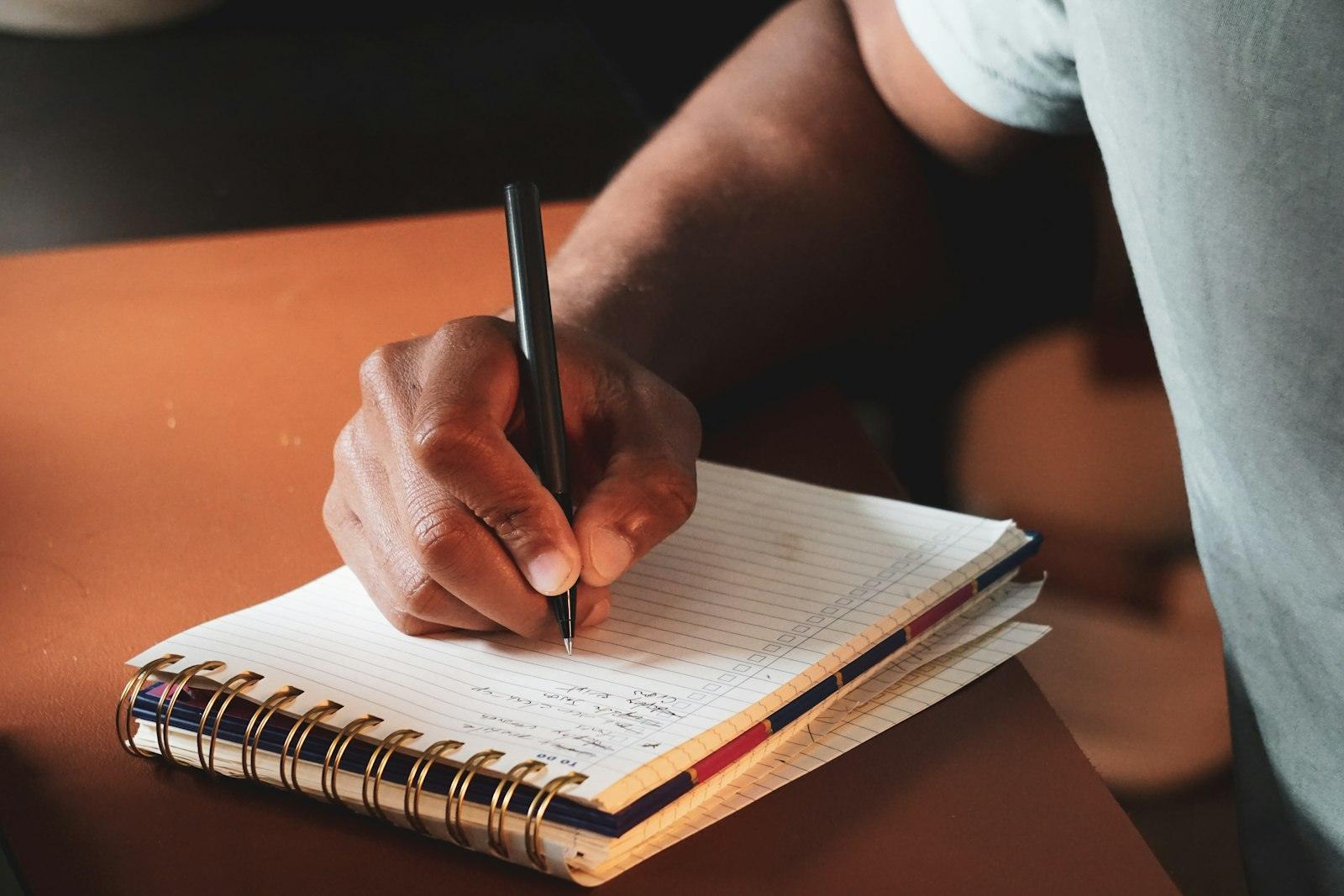Eine Person schreibt ihre gewünschte Zukunft und den nächsten kleinen Schritt in ein Notizbuch