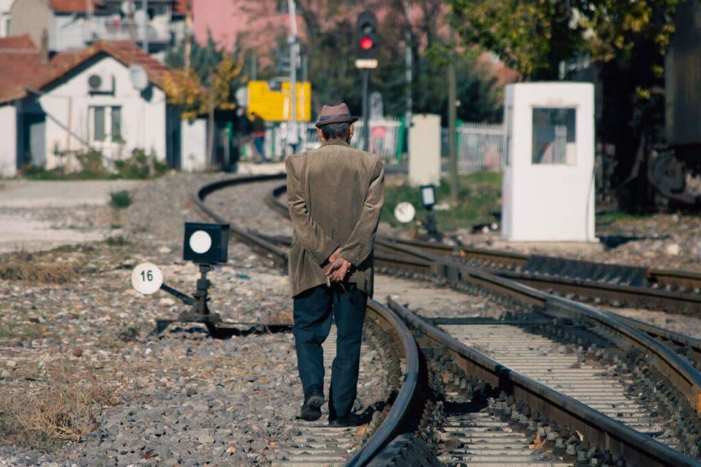 Ein Mann steht nachdenklich vor Bahngleisen, die sich in verschiedene Richtungen teilen – Sinnbild dafür, dass ein alter Lebensplan nicht mehr zum heutigen Ich passt