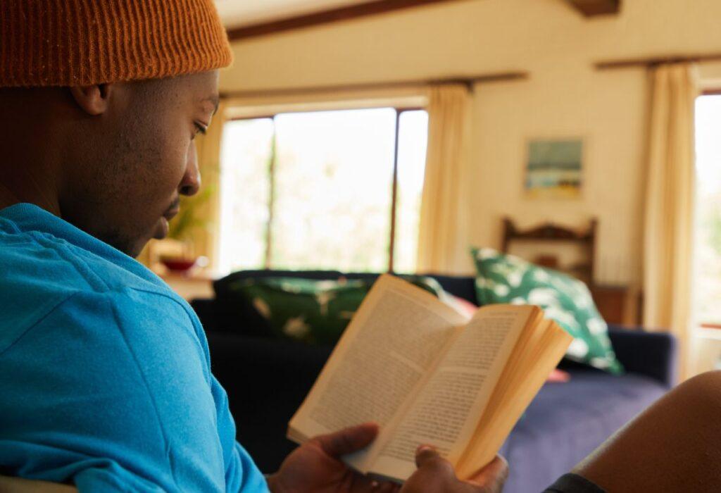 Ein Mann liest entspannt ein Buch in seinem gemütlichen Wohnzimmer – Sinnbild für den Buchtipp The Big Leap über verborgene Ängste und Grenzen