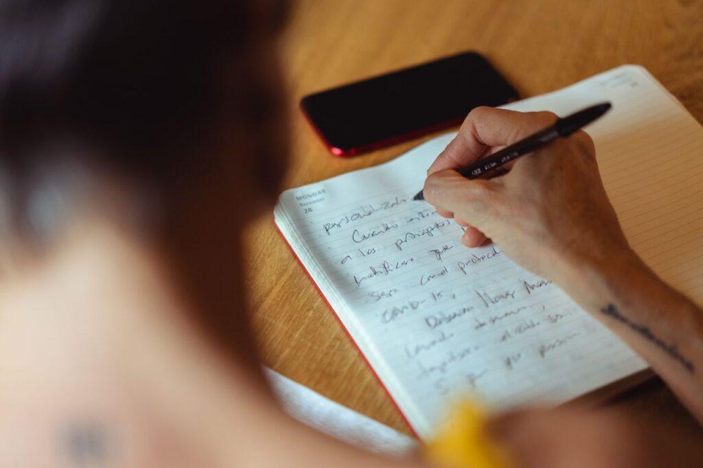 Eine Person ordnet Fakten, Gedanken und Gefühle handschriftlich in einem Notizbuch